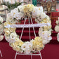 A Large Wreath by FlowersonNortonSt, featuring an opulent arrangement of white and cream roses and orchids, is beautifully presented on a stand. Adorning the premium wreath is a ribbon with the heartfelt message: "We will love you forever Nonna Amilia, Toto, Chiara, Siena & Bianca." This magnificent piece enhances the ambiance inside a church.