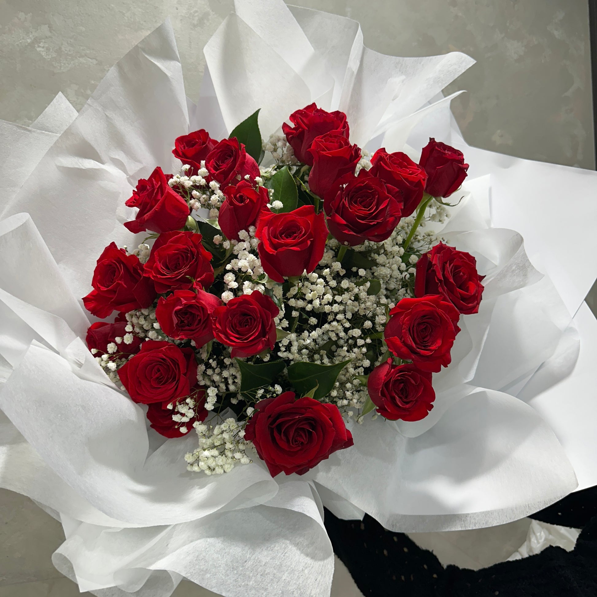 The Classical Lovers Red Rose Bouquet by Flowers on Norton St features lush red roses in elegant white paper with delicate baby's breath accents, perfect for classical lovers.