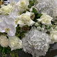 Introducing the "Florist Choice - White" from Flowers on Norton St, a sophisticated arrangement of lush white flowers, including roses, hydrangeas, orchids, and chrysanthemums elegantly complemented by green foliage. This exquisite bouquet is perfect for any occasion and comes with our affordable flower delivery service in Sydney.