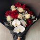 The Red and White Bud + Bloom Rose Bouquet from Flowers on Norton St features red and white roses, elegant white orchids, and delicate baby's breath, all beautifully wrapped in sleek black paper.