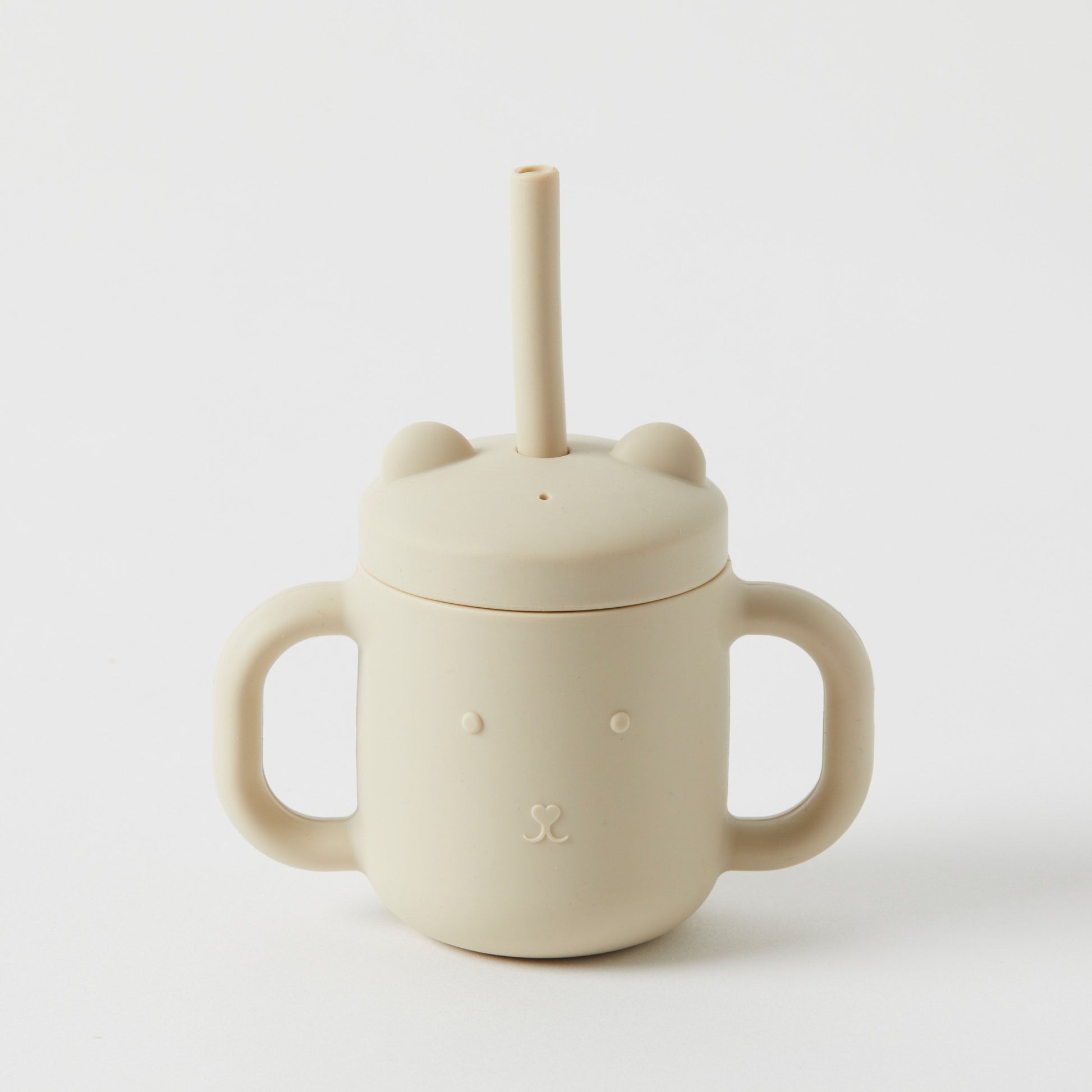 The Silicone Sippy Cup with Straw by Flowers on Norton St is a beige, BPA-free, non-toxic silicone cup featuring handles and a lid with bear ears and a subtle bear face design. A straw extends from the top, and the cup is elegantly displayed against a white background.