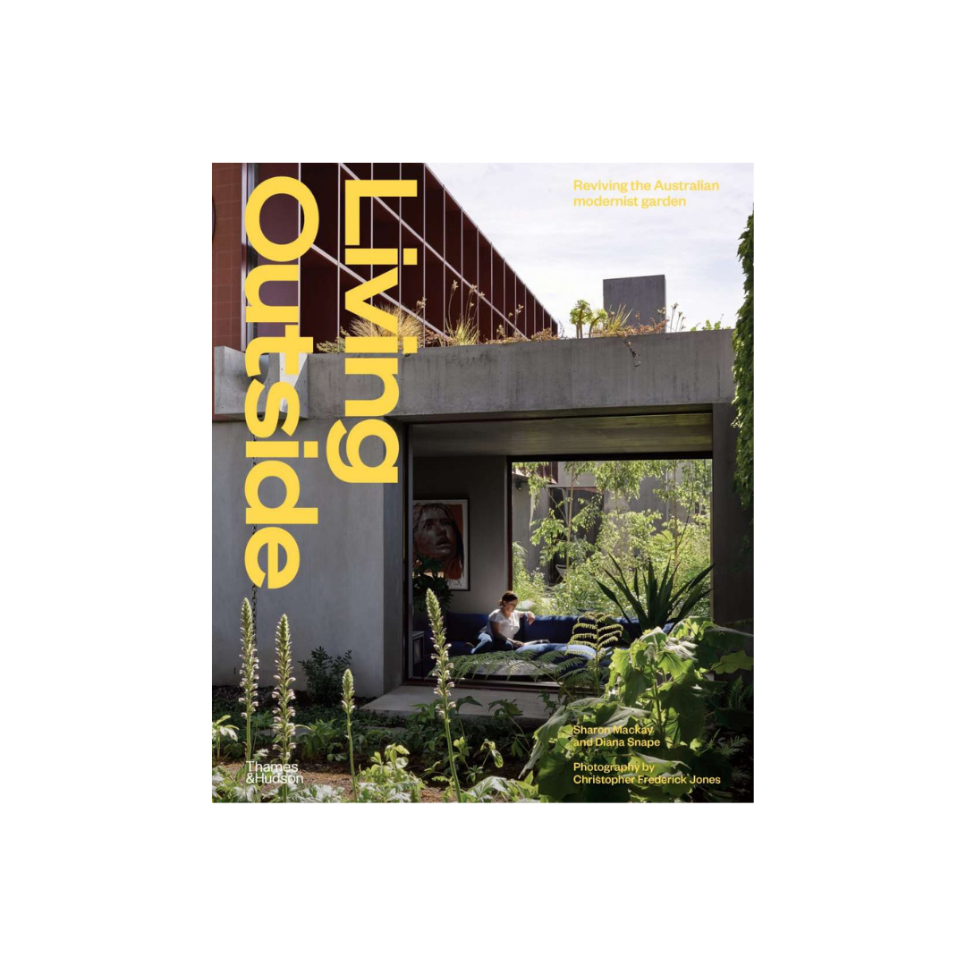 The image is a book cover featuring "Living Outside" in bold yellow text. It shows a person relaxing with a book on a sofa amidst lush greenery, framed by concrete architecture, encapsulating the essence of Australian garden design with outdoor rooms and native plants. Additional text highlights modernist gardens. The product is presented by Flowers on Norton St.