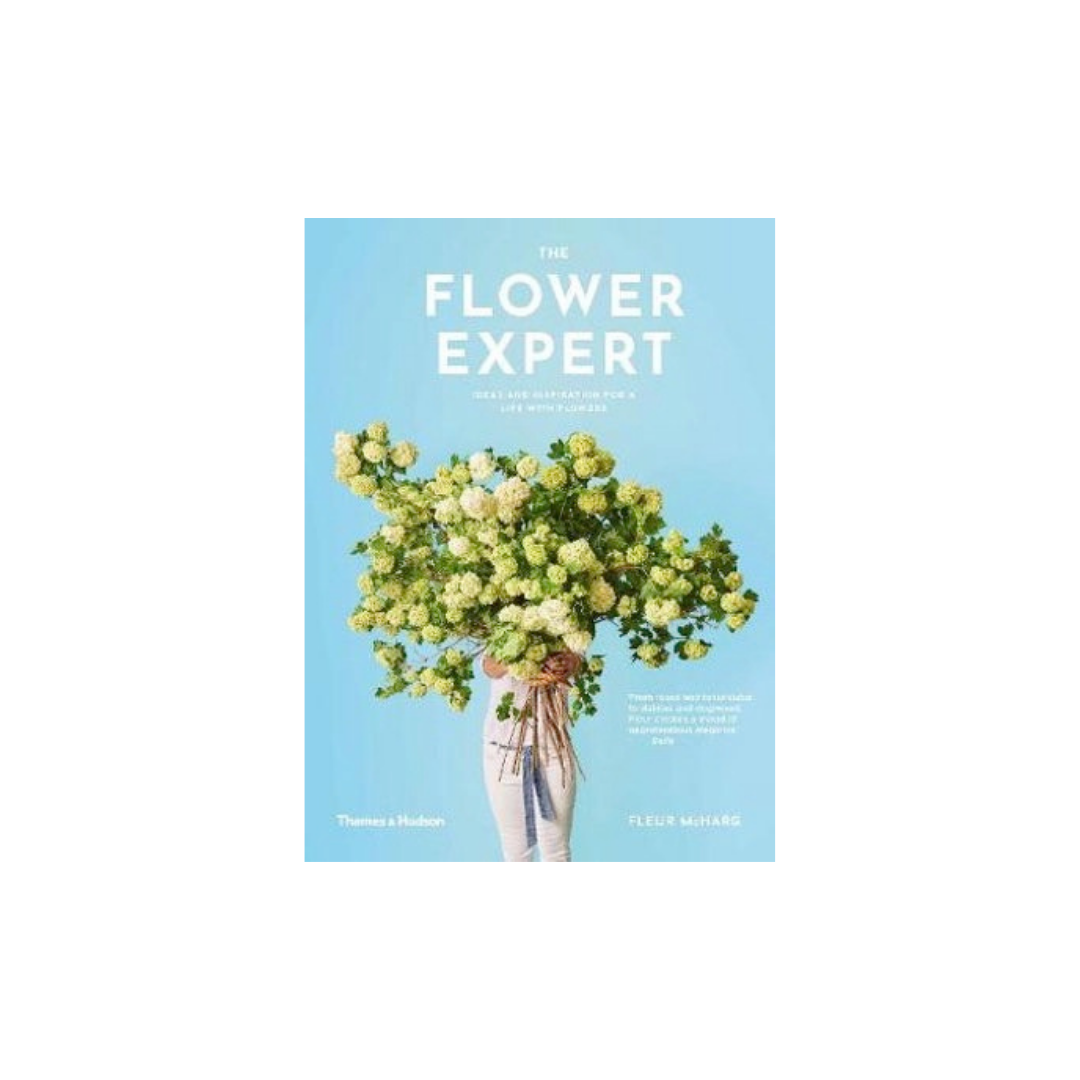 The book cover for "The Flower Expert" from Flowers on Norton St features innovative floral designs by Fleur McHarg, depicted with a person holding an oversized bouquet of green and cream flowers. The light blue background enhances its charm, accompanied by a quote celebrating Fleur's remarkable expertise in the floral world.