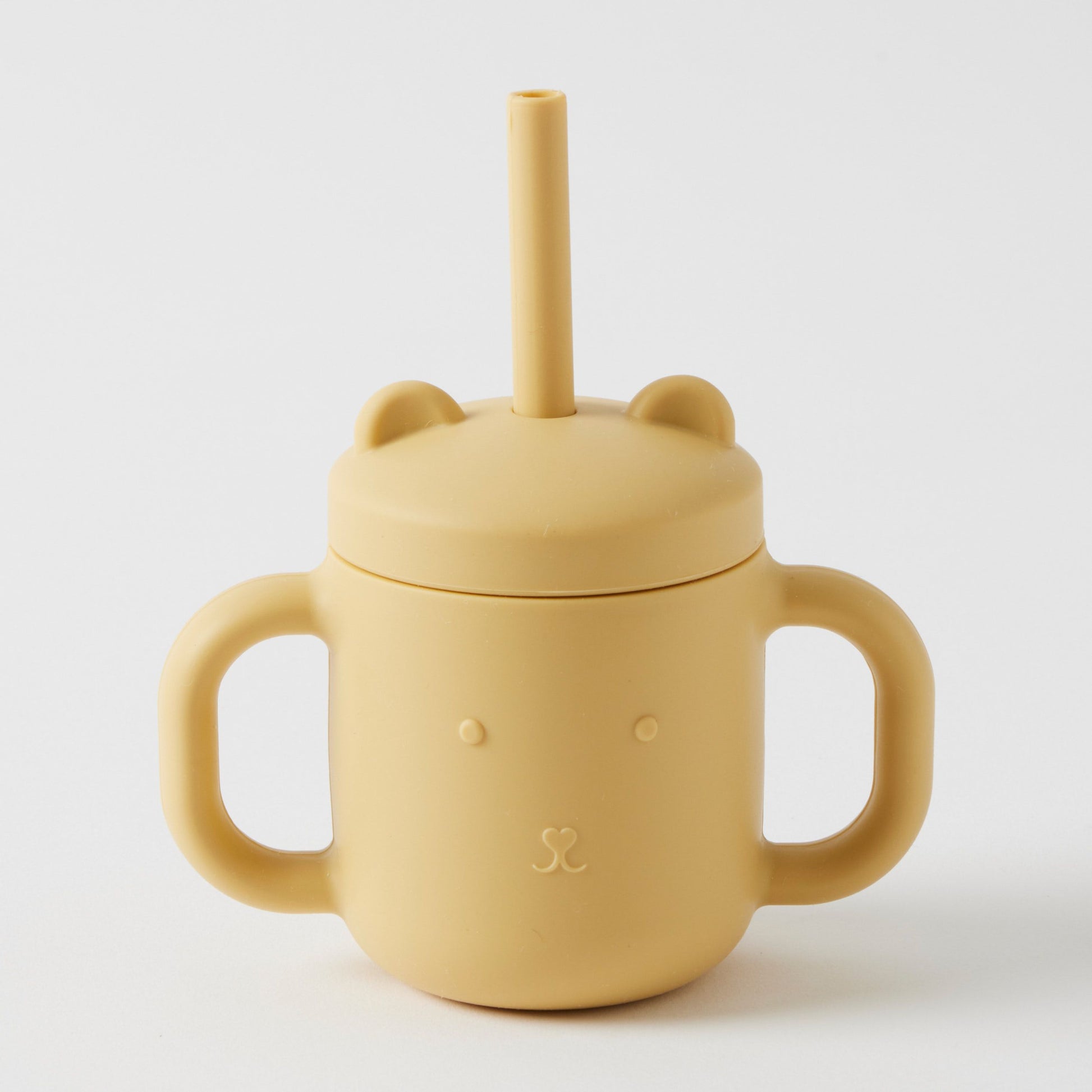 The Flowers on Norton St Silicone Sippy Cup with Straw is a BPA-free, non-toxic silicone sippy cup in yellow. It features a lid shaped like a bear's face and ears, two handles, and is designed for safe sipping by toddlers.