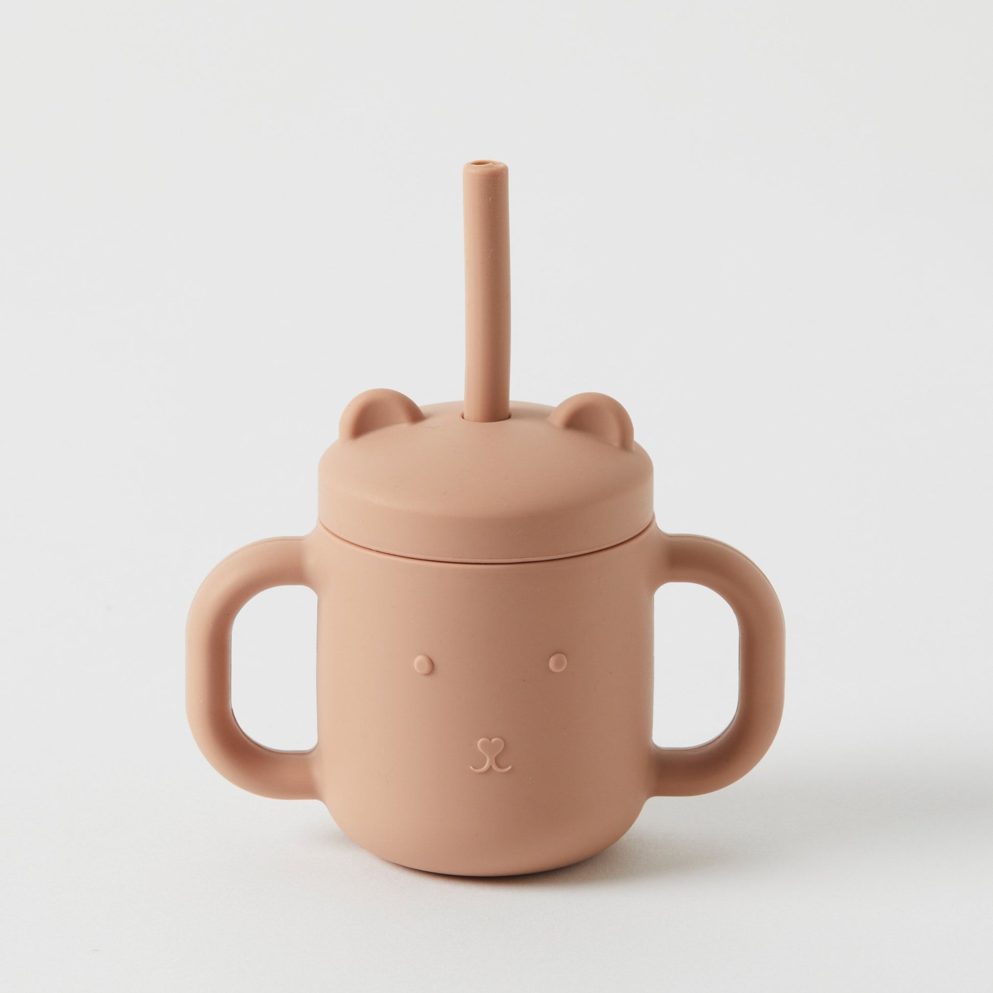 Introducing the Silicone Sippy Cup with Straw by Flowers on Norton St—a light brown sippy cup crafted from non-toxic, BPA-free materials. Designed with two handles and a bear face lid complete with bear ears, this cup includes a centrally placed straw for safe sipping.