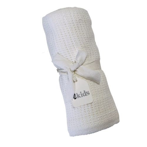 A rolled-up white knitted Baby Blanket from FlowersonNortonSt, tied with a white ribbon, awaits, perfect for snuggling. A tag labeled "kids" invites little ones to enjoy its cuddly softness.